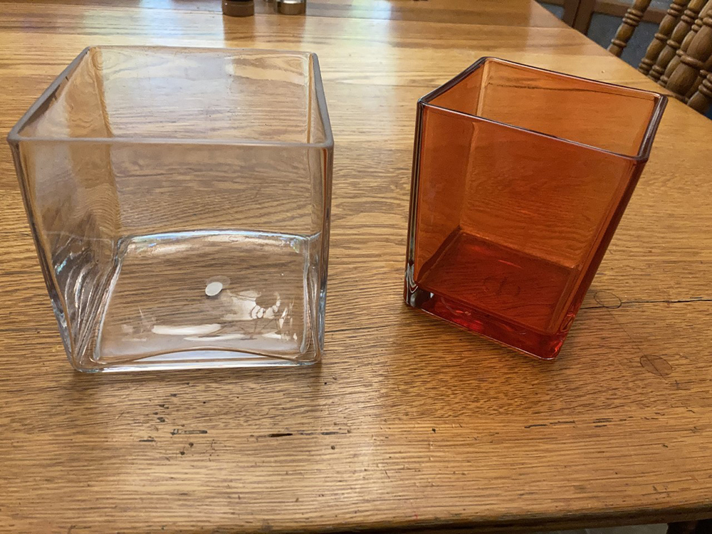 Two 5″ square glass vases, 1 clear, 1 red for flowers, small candles, etc.