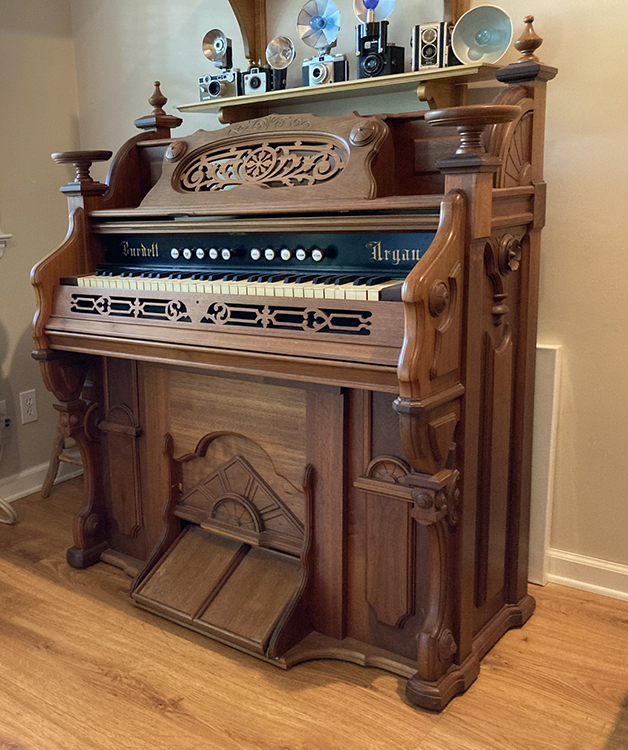 Vintage Burdett brand ornate Victorian pump organ of solid walnut with beautiful pull-stops, music stand, pull-down cover, and lots of curvy designs all around